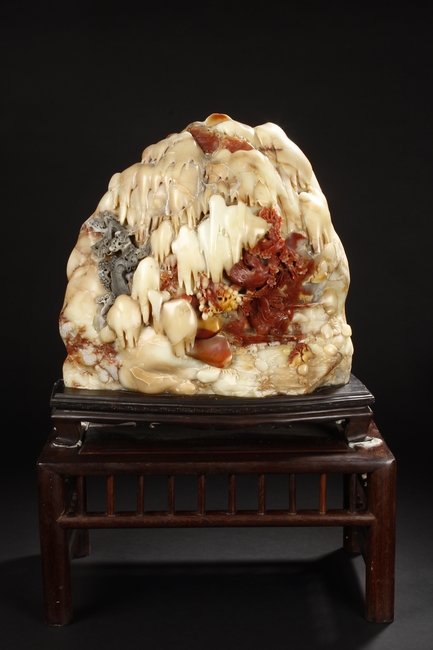 A LARGE CARVED SOAPSTONE BOULDER SHANZI: The large boulder Shanzi cleverly carved to a mountain and river scene, with an elder fishing on his boat, below plum flower trees, close to pine trees and mountains, two birds snatching up fishes clo