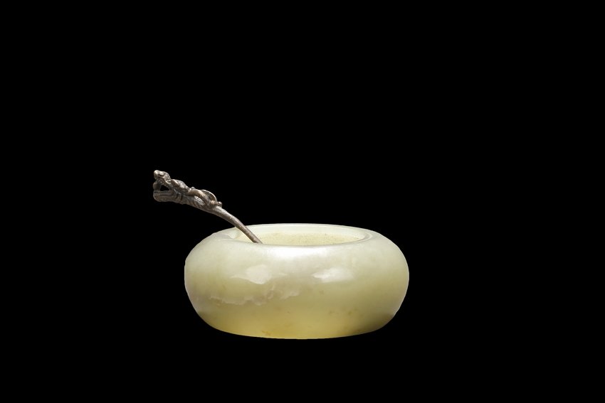A CARVED CELADON JADE WASHER: Of compressed globular form, the washer with a small round opening on top, the stone of celadon color with natural features, and the spoon with a dragon head and pearl handle. Qing Dynasty period. W: 