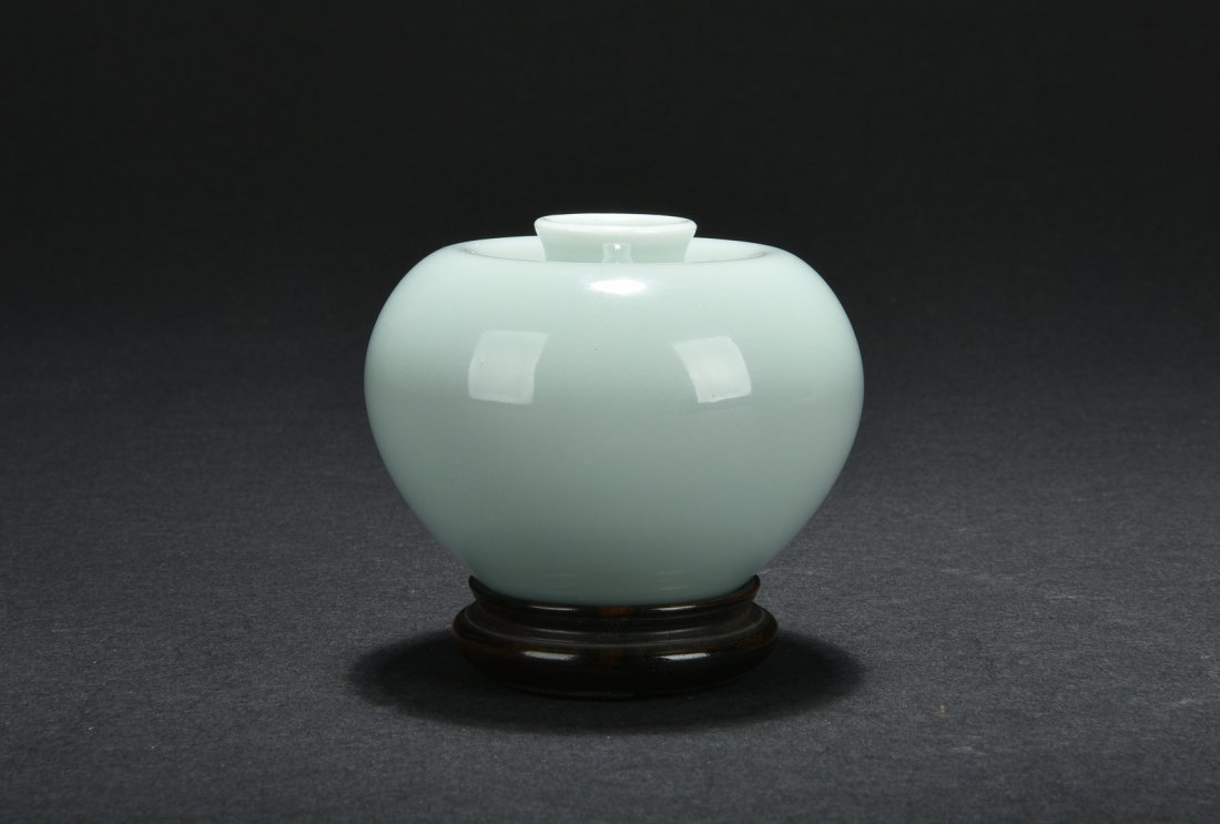 CELADON GLAZED SMALL JAR, ZUN: Of apple shape, the small jar glazed overall in celadon, with short neck concaved slightly into the body and flared rim, bottom bears six character DAOGUANG mark. Includes wooden stand. H: 2 1/4 in (8