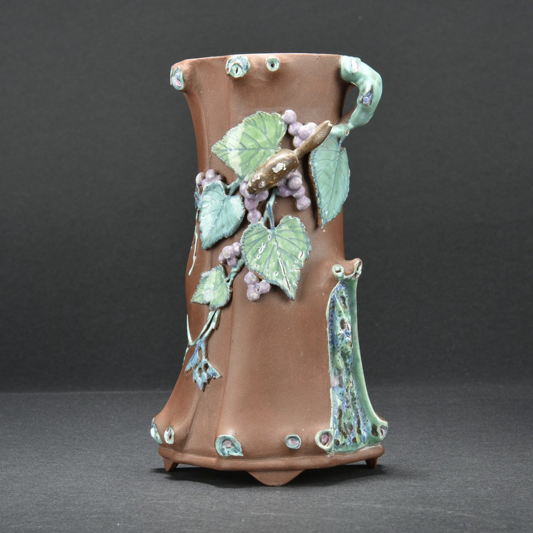 YIXING ZISHA 'TREE TRUNK' WALL VASE: Crafted in naturalistic tree trunk form, with painted branches, leaves, and flowers on the side, the back with two character artist mark. H: 6 3/4 in (17.1 cm) W: 3 7/8 in (9.8 cm)
