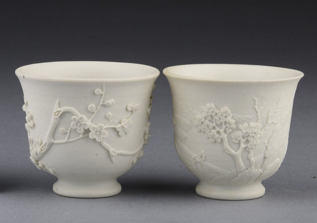 PAIR CARVED AND UNGLAZED CERAMIC CUPS: One cup carved with magpie birds perched on plum flower trees, the other cup carved with mountain landscape, both cups unglazed. 19th C. H: 2 in (5.1 cm) D: 2 1/4 in (5.7 cm)