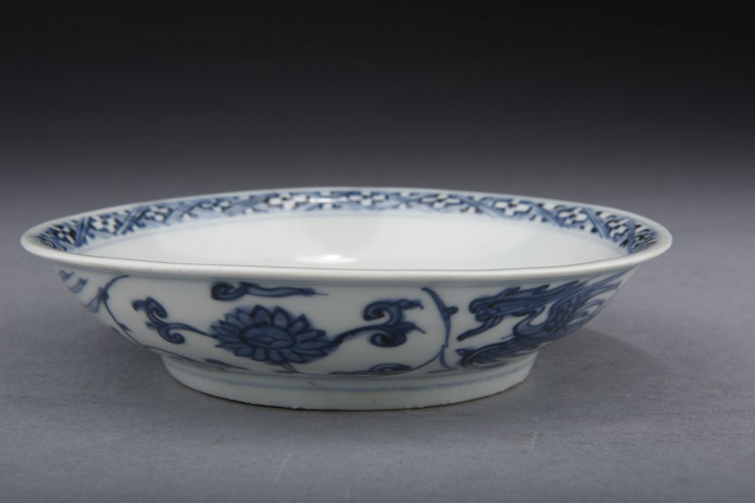BLUE AND WHITE 'DRAGON' DISH: The exterior painted with flying dragons, the interior painted with pine tree, with patterned band on the rim, bottom bears four character 'XUANDE' mark. Early Ming Dynasty period. D: 5 7/8 in (14.9 c