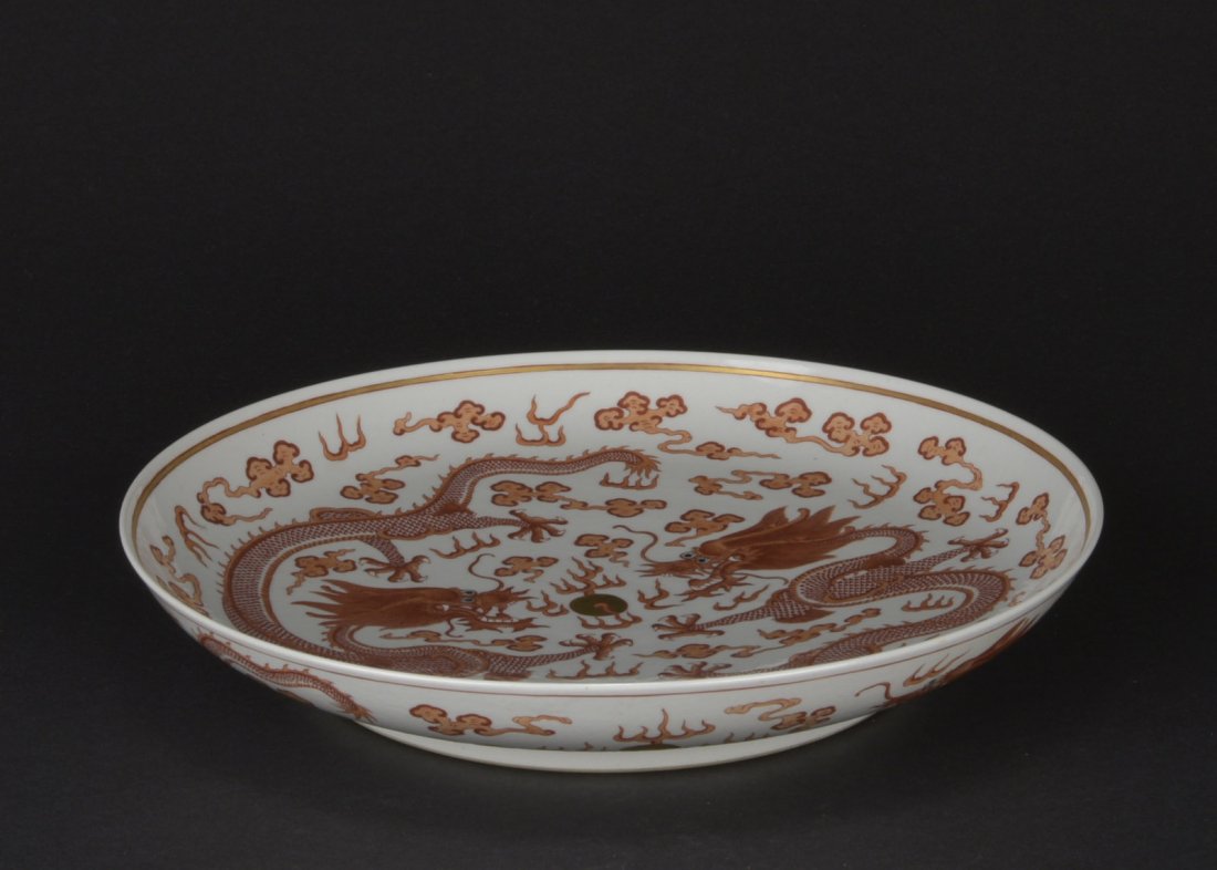 UNDERGLAZE RED 'TWIN DRAGONS' CHARGER: The underglaze red charger depicts two confronting five claw dragons flying amidst ruyi clouds chasing after flaming sphere, bottom with six character 'XUANTONG' mark. 19th C. D: 13 5/8 in (34.5 cm)
