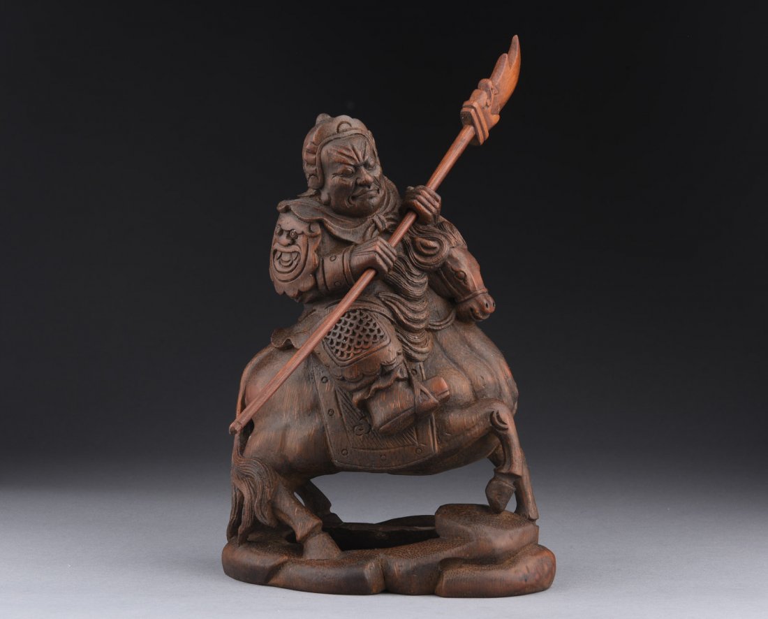 BAMBOO CARVED WARRIOR ON HORSE FIGURE: The carving depicts an armored warrior on a galloping horse while holding a large halberd with both hands, the warrior with stern facial expression. H: 9 1/2 in (24.1 cm)