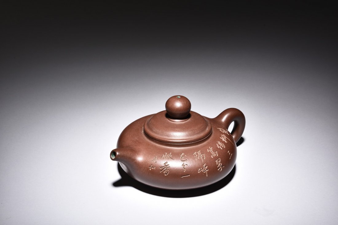 YIXING ZISHA 'POETRY' TEAPOT: Of compressed form, the teapot's brown exterior incised with poetry calligraphy, the interior glazed in green, with children and lady outlined, bottom bears artist mark.