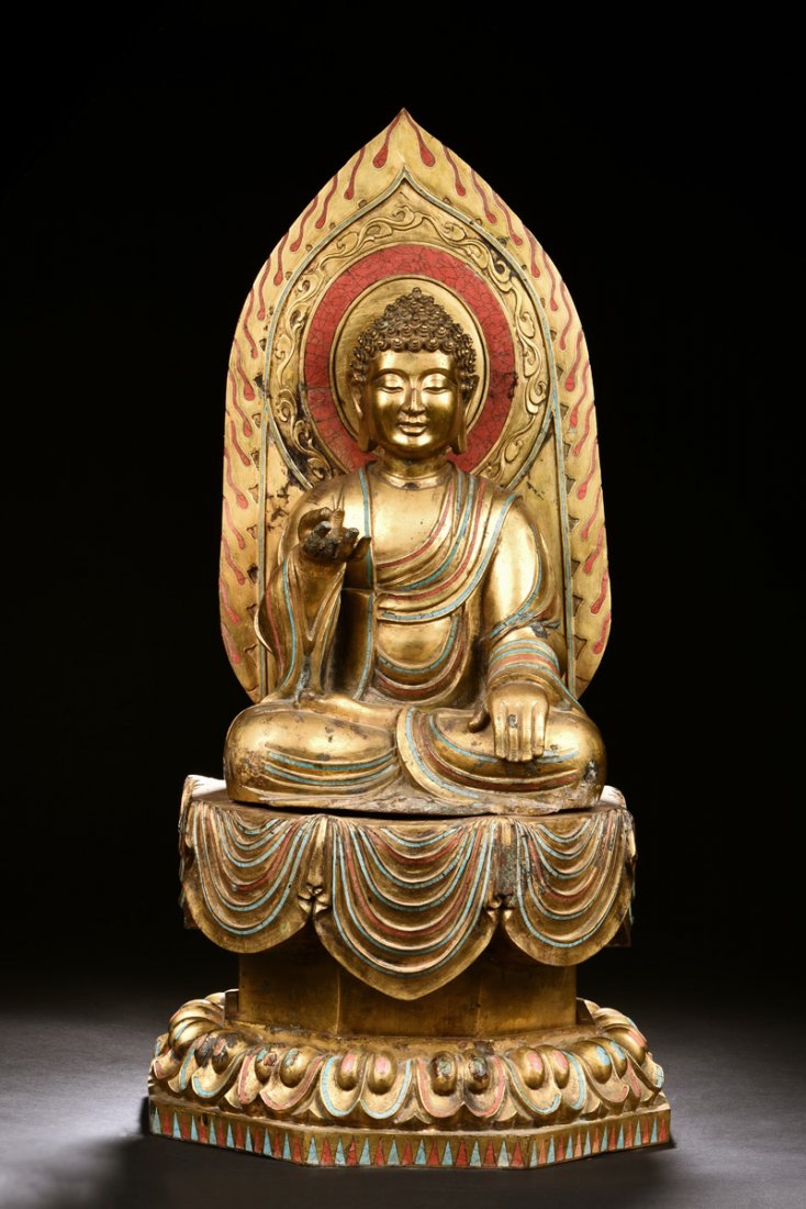 GILT BRONZE SEATED AMITABHA FIGURE: The gilt bronze Amitabha seated on top of a raised pedestal above lotus throne pad, back against fiery mandorla, one hand raised to chest level and the other rests on leg, dressed in flowing robe, eye
