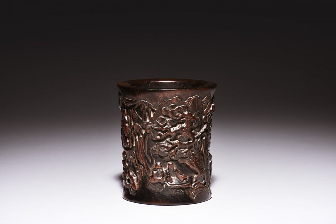 ZITAN WOOD CARVED BRUSH POT: The brush pot carved in relief on the exterior, depicts two elders playing musical instruments beneath pine trees and bamboo trees in outdoor setting, the reverse depicts elders engaged in other leisu