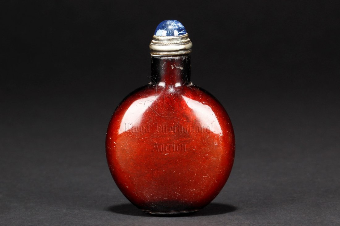 REDDISH-BROWN GLASS SNUFF BOTTLE: Of flattened ovoid form, the body with reddish-brown color, with blue stopper. Height: 2 7/8 in (7.3 cm)