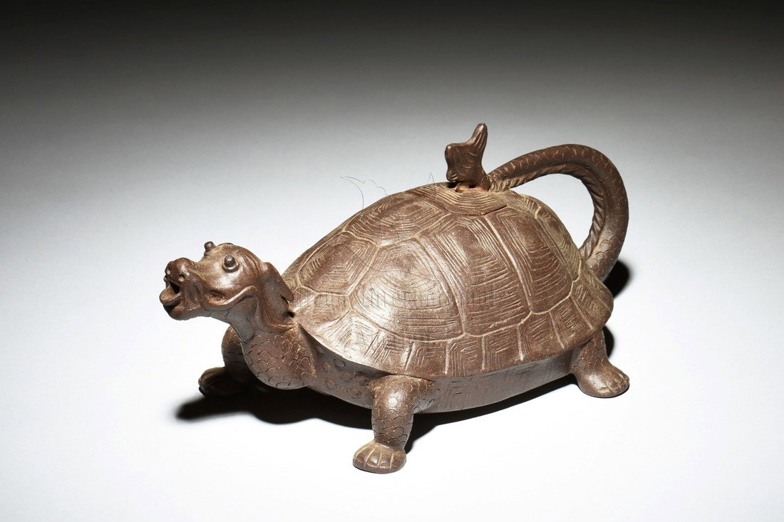 YIXING ZISHA 'DRAGON TURTLE' TEAPOT: The teapot in the shape of a mythical dragon turtle, with the tail as handle, tail tip as finial, and mouth as spout, the clay is of chocolate brown color tone, small mark on the bottom. Height: 4 in 
