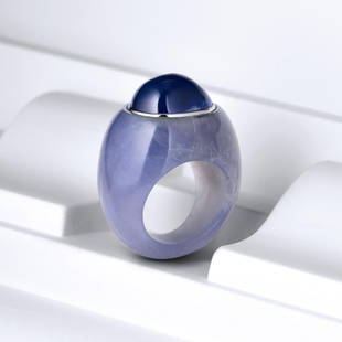 Suzanne Belperron Sapphire Chalcedony Ring: An oval cabochon sapphire weighing approximately 12 carats set in a carved blue chalcedony ring with a gray gold bezel; ring size 3-3/4; measures 5/8 inches at widest point; weight 12.80 g. Accompanie