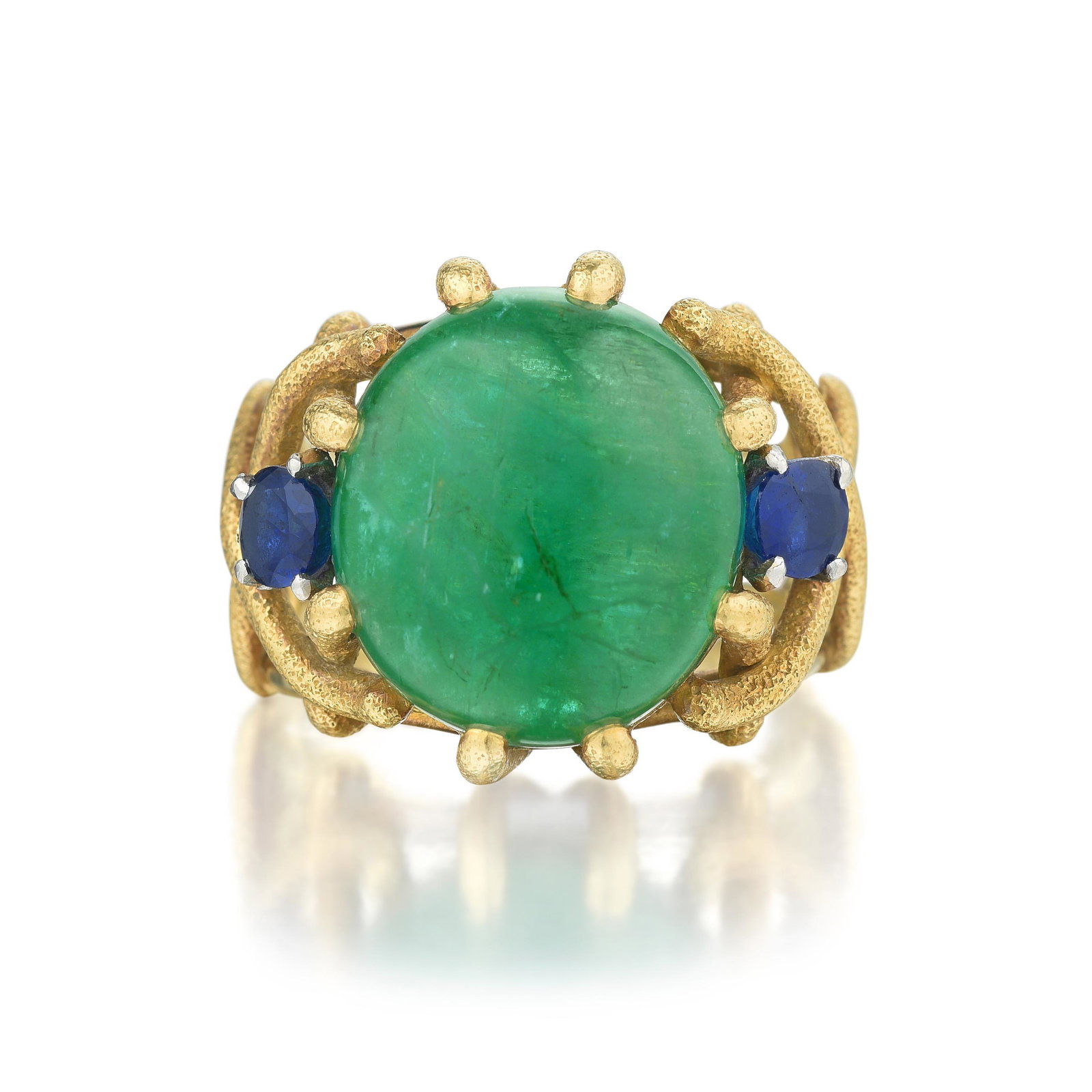 Louis Feron Cabochon Emerald Ring: METAL: 18K gold GEMSTONE(S): cabochon emerald approx. 10.85 carats; oval-cut sapphires approx. 0.90 carat total MEASUREMENTS: 3/4 inch at widest section RING SIZE: 7 WEIGHT: 14.40 g.