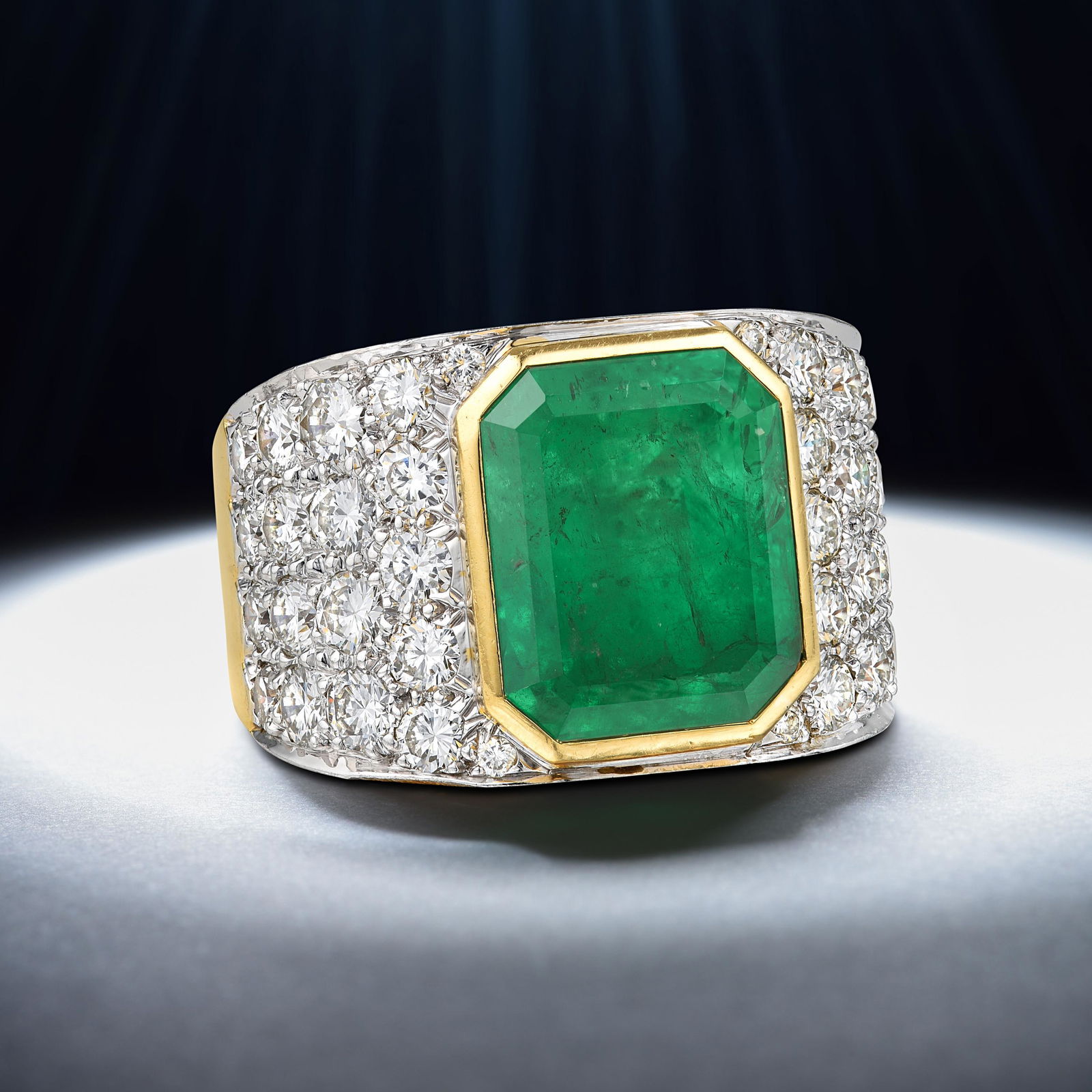 David Webb Colombian Emerald and Diamond Ring: Crafted in 18K yellow gold and platinum; featuring an emerald-cut emerald weighing approximately 10.45 carats; surrounded by round brilliant-cut diamonds weighing a total of approximately 3.10 carats,