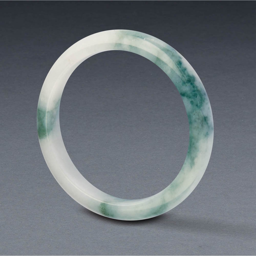 A JADEITE BANGLE: A JADEITE BANGLE Outer diameter, inner diameter and thickness approximately 72.87 x 57.86 x 11.86mm. Accompanied by Hong Kong Jade & Stone Laboratory certificate stating that the jadeite is natural, k