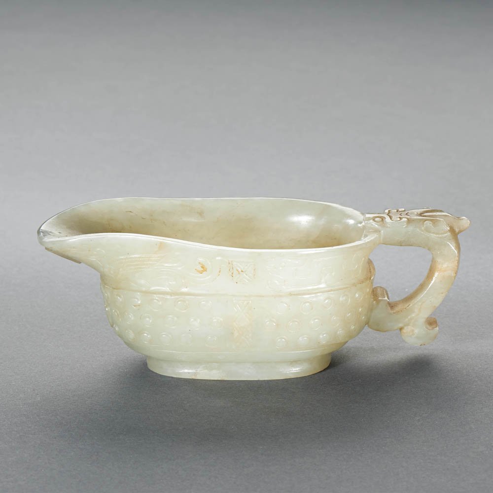 A CHINESE WHITE JADE 'DRAGON AND PHOENIX' VESSEL, YI: MING DYNASTY (1368-1644) A CHINESE WHITE JADE 'DRAGON AND PHOENIX' VESSEL, YI 明 白玉雕「龍鳳」「乳丁」紋匜 L 13 cm.