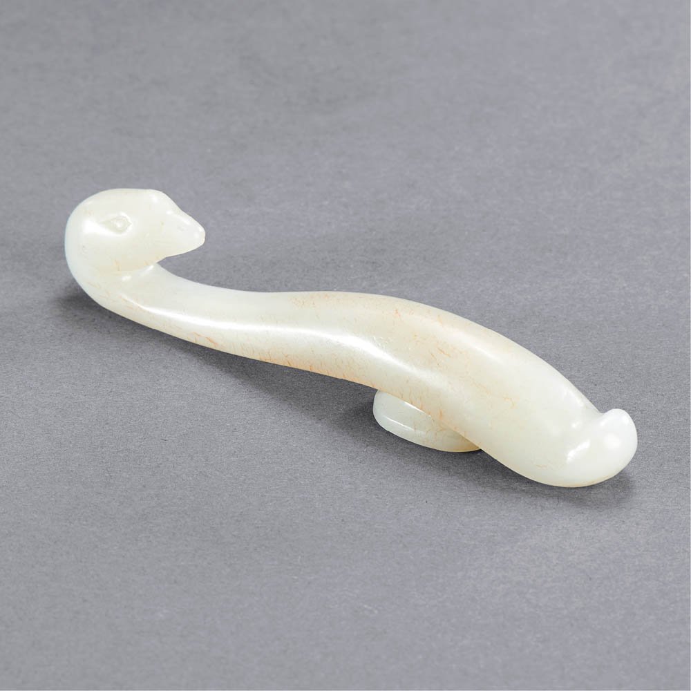 A CHINESE WHITE AND RUSSET JADE GOOSE BELT HOOK: MING DYNASTY (1368-1644) A WHITE AND RUSSET JADE GOOSE BELT HOOK L 10.5 cm. (4 in.) 明 白玉帶沁鵝首帶鉤