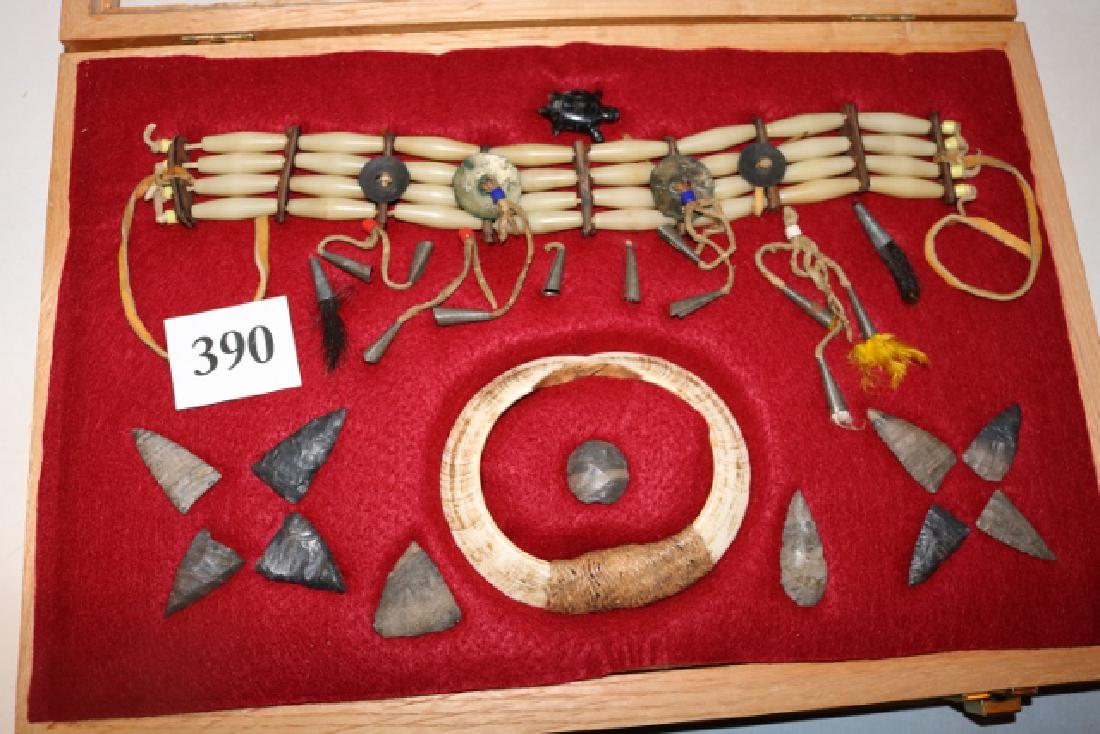 11 Flints, 15” Bone Choker: 12” x 18” Wood Frame containing 11 Flints, 15” Bone Choker with tin cone and trade bead drops, small turtle effigy and circular shell breast plate