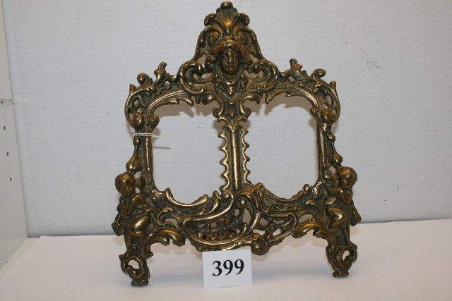 Brass double picture frame: Brass double picture frame with a Jenny Lind head and cupids. 12" high and 10 1/2" wide