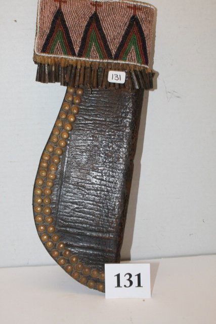 Crow Knife Scabbard: 12 ½” x 5 1/8” Crow Knife Scabbard, fine bead work on saddle leather with tin cones, brass tacks, patinated, fine condition, shows good age