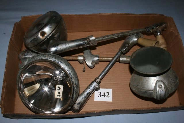 Three spot lights: Three spot lights with Bakelite handles. One handle split, one has attached mirror, 15” from grip to light, 2 with 4” lens one with 5 ½” lens, two made by UNITY, one unmarked.