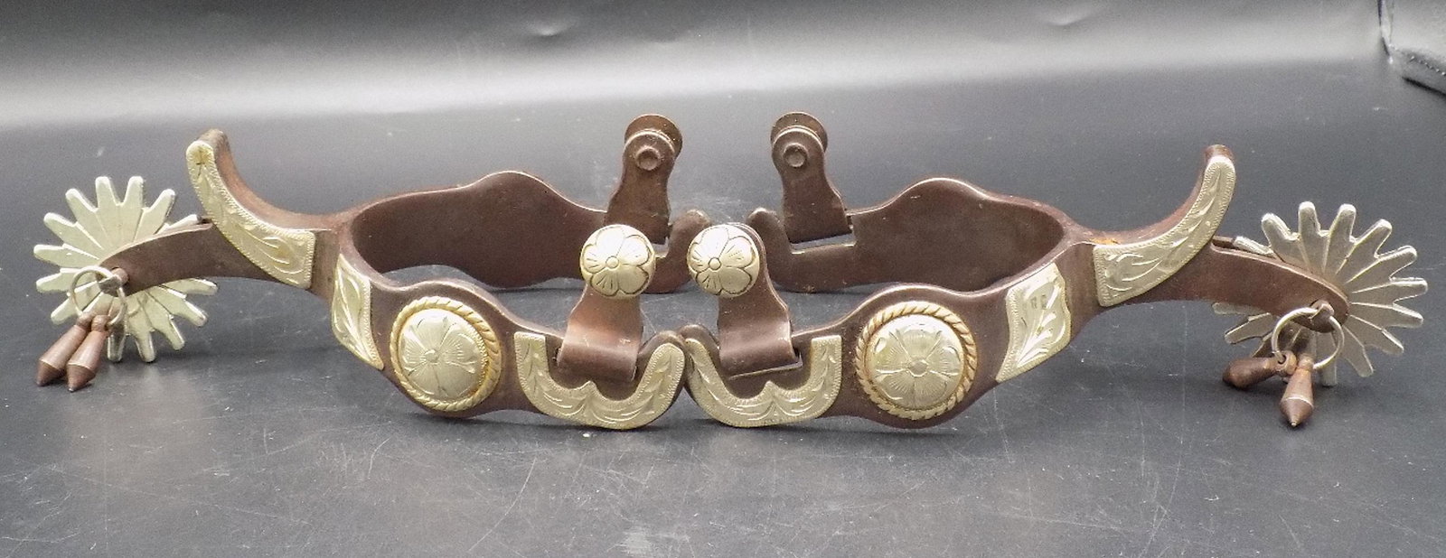 Nicely engraved silver mounted spurs: Nicely engraved silver mounted spurs. Did not find a maker’s marking. Have a nice jingle sound. Measure 2 7/8” at heal. Approximately 6” long