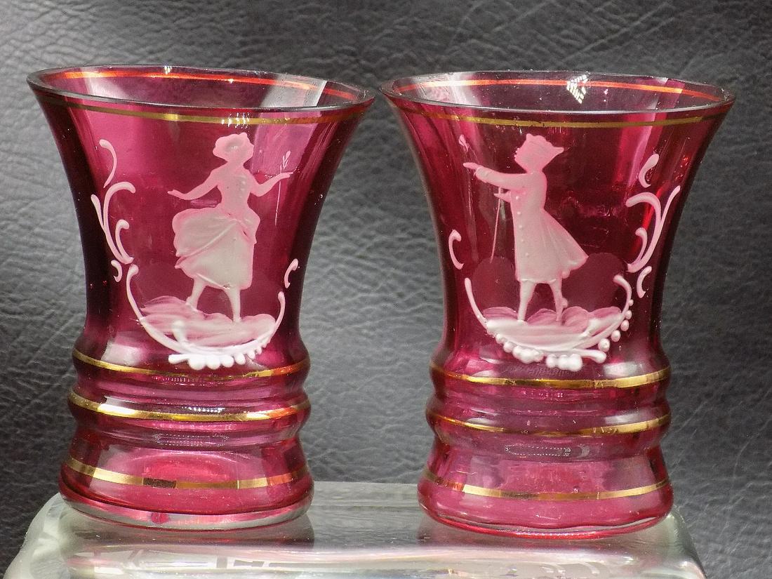 Vintage pair of enamel decorated cranberry art glass shot glasses: Vintage pair of enamel decorated cranberry art glass shot glasses. Enamel decorated with classical figures. 3 inches tall x 2 ¼ wide at top rim