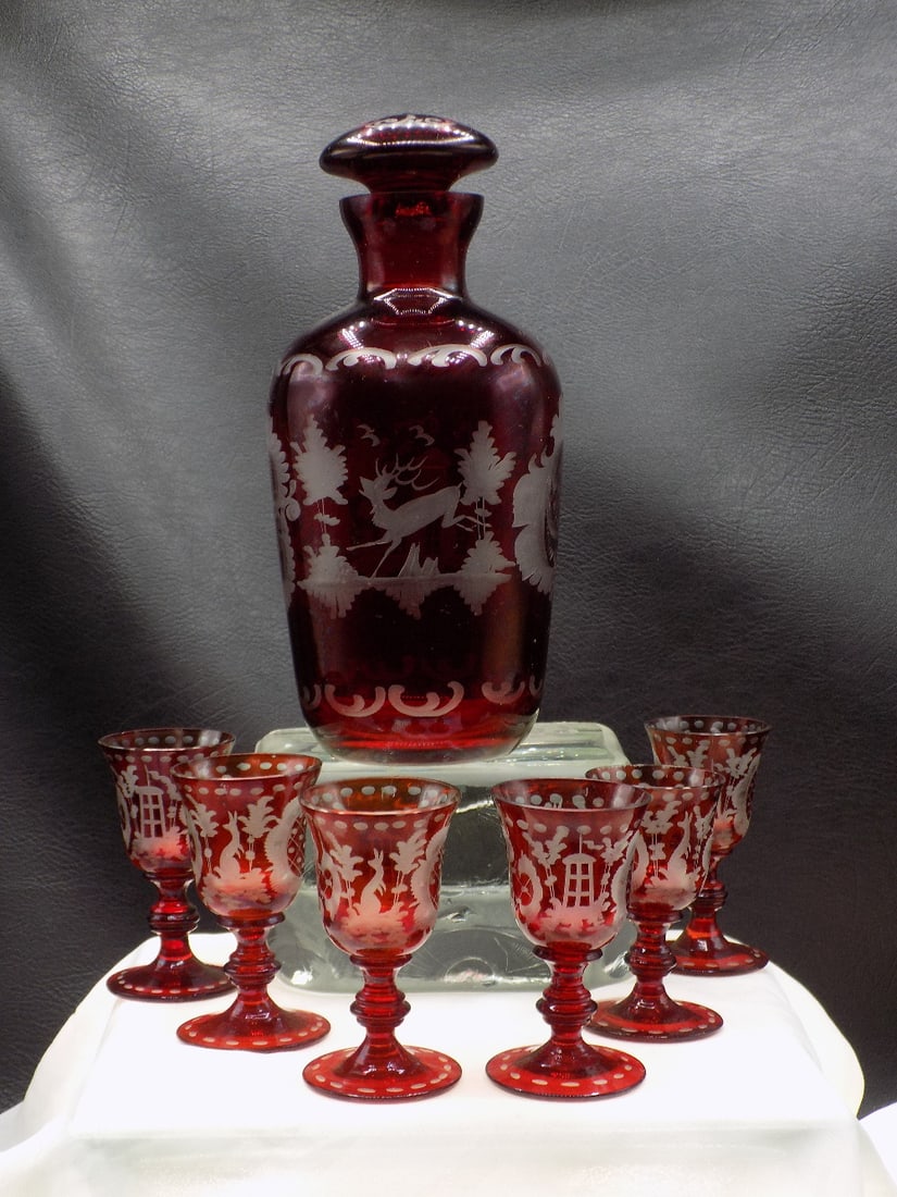 Elaborate vintage cranberry cut to clear art glass liquor set: Elaborate vintage cranberry cut to clear art glass liquor set. Bottle with 6 glasses. With cut glass deer, castle and foliage. Beautiful colors. Great quality and detail. In very good original as foun