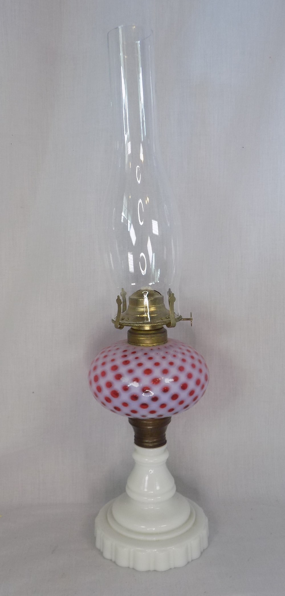 1800s Fenton cranberry opalescent diamond quilted coin spot oil lamp: 1800s Fenton cranberry opalescent diamond quilted coin spot oil lamp. Milk glass base. Beautiful colors. In very good original as found condition. 22 inches tall to top of chimney. Lamp base is 11 &fr