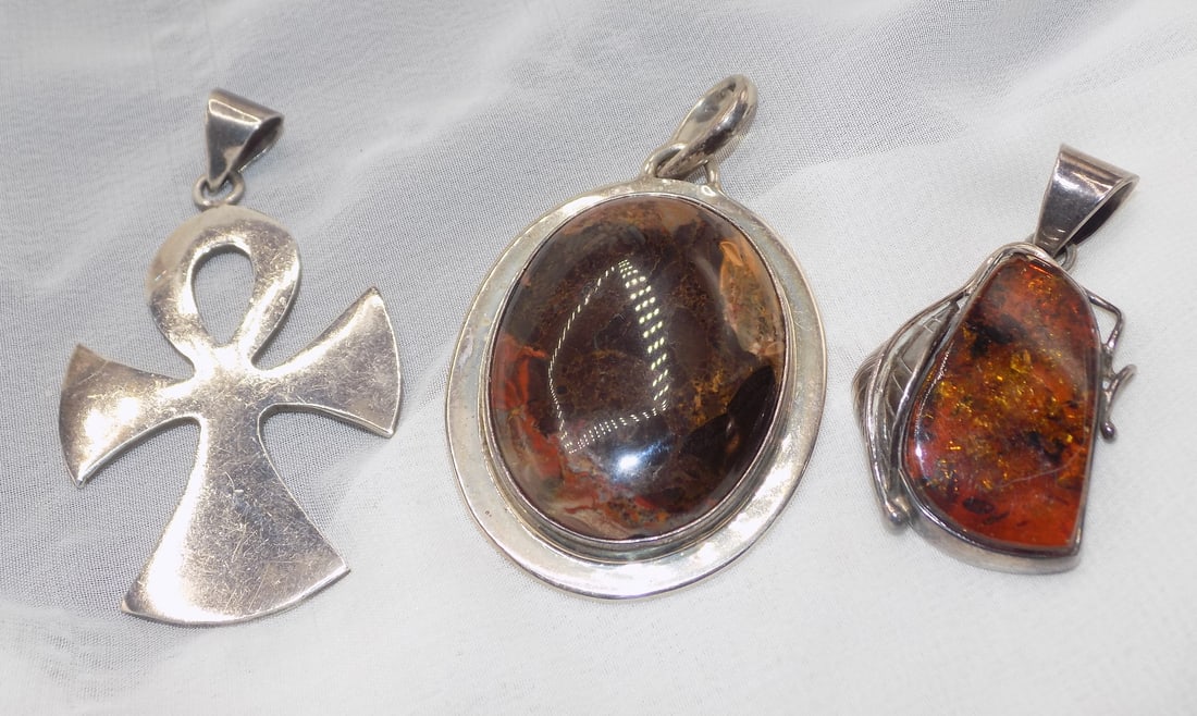 Three vintage marked sterling pendants: Three vintage marked sterling pendants. Center pendant is a Mexican fire agate 2 ½. Baltic amber pendant and sterling cross pendant 2 ½ inches tall. Beautiful colors. In very good origin