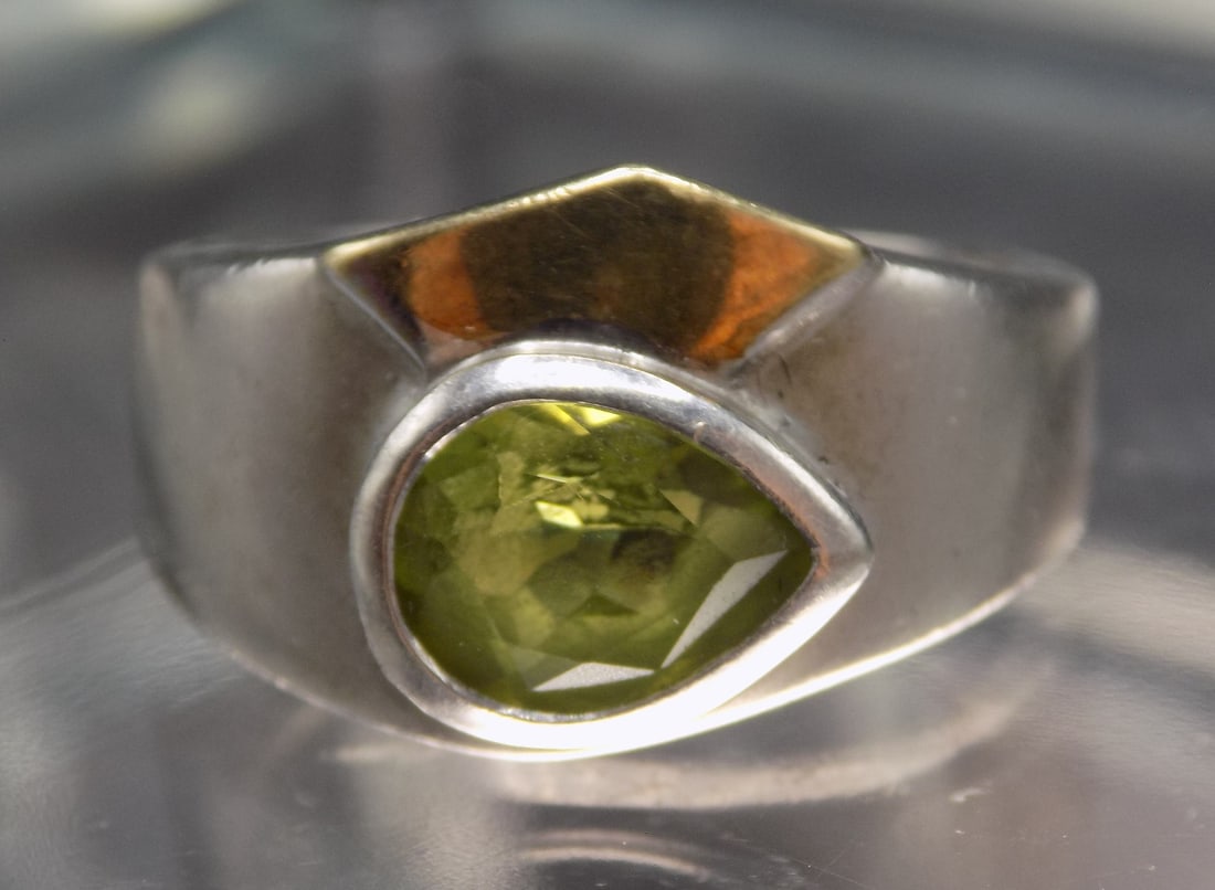 Beautiful 2 ct peridot sterling silver and gold ring: Beautiful 2 ct peridot sterling silver and gold ring. Size 7 ½ . For in house shipping, please call Mike at Thriftiques 319-321-0613