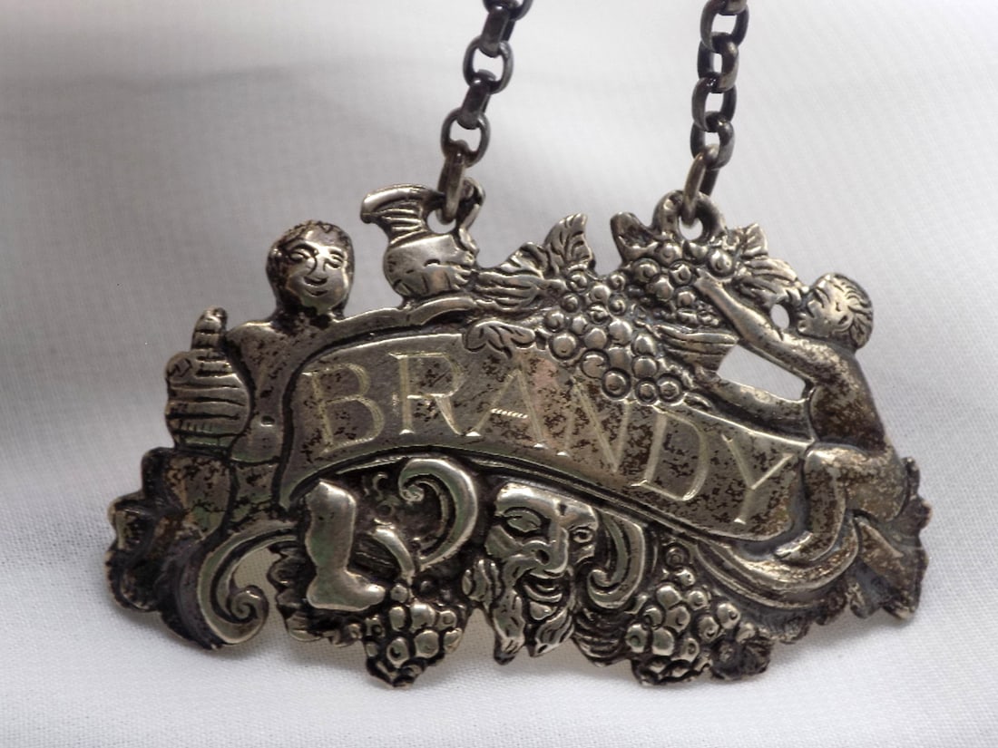 Ornate vintage sterling silver brandy liquor bottle label: Ornate vintage sterling silver brandy liquor bottle label. Marked as shown in photo. In very good original as found condition. Great quality and detail. 2 1/8 x 1 ¼ inches, does not include chain