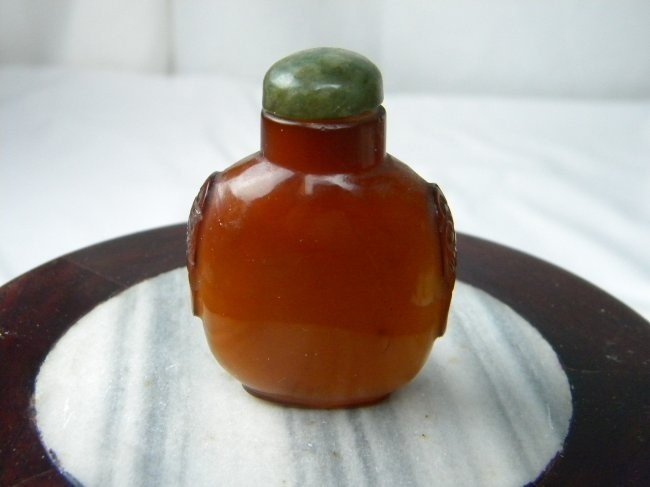 A CARNELIAN SNUFF BOTTLE WITH JADE STOPPER, QING: A CARNELIAN SNUFF BOTTLE WITH JADE STOPPER, QING DYNASTY, TWO LION HEAD ON THE SIDE, 2.25" X 1.5"