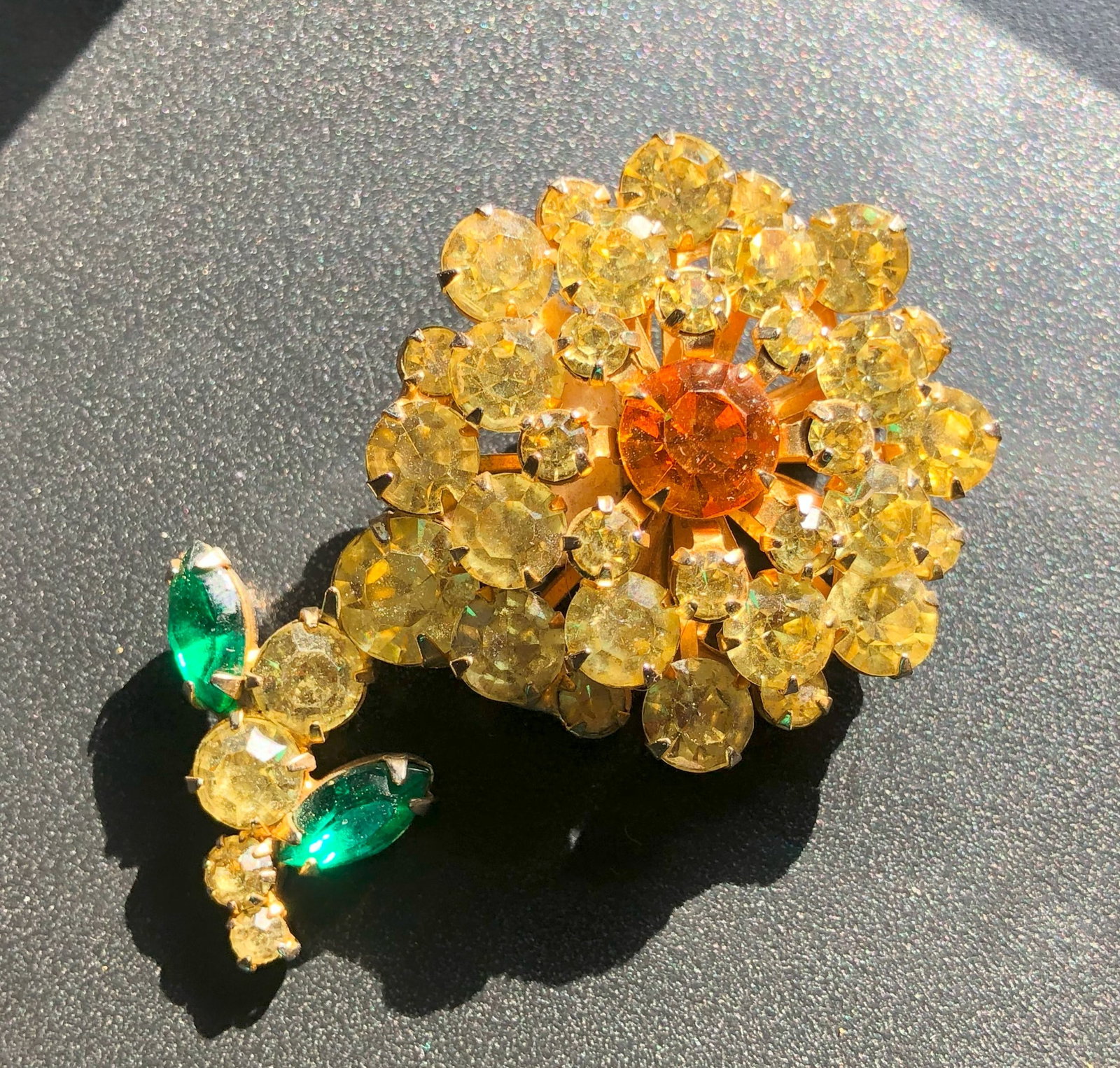 Vintage Floral Brooch: A stunning vintage floral brooch with yellow and orange gemstones, accented with green leaves.