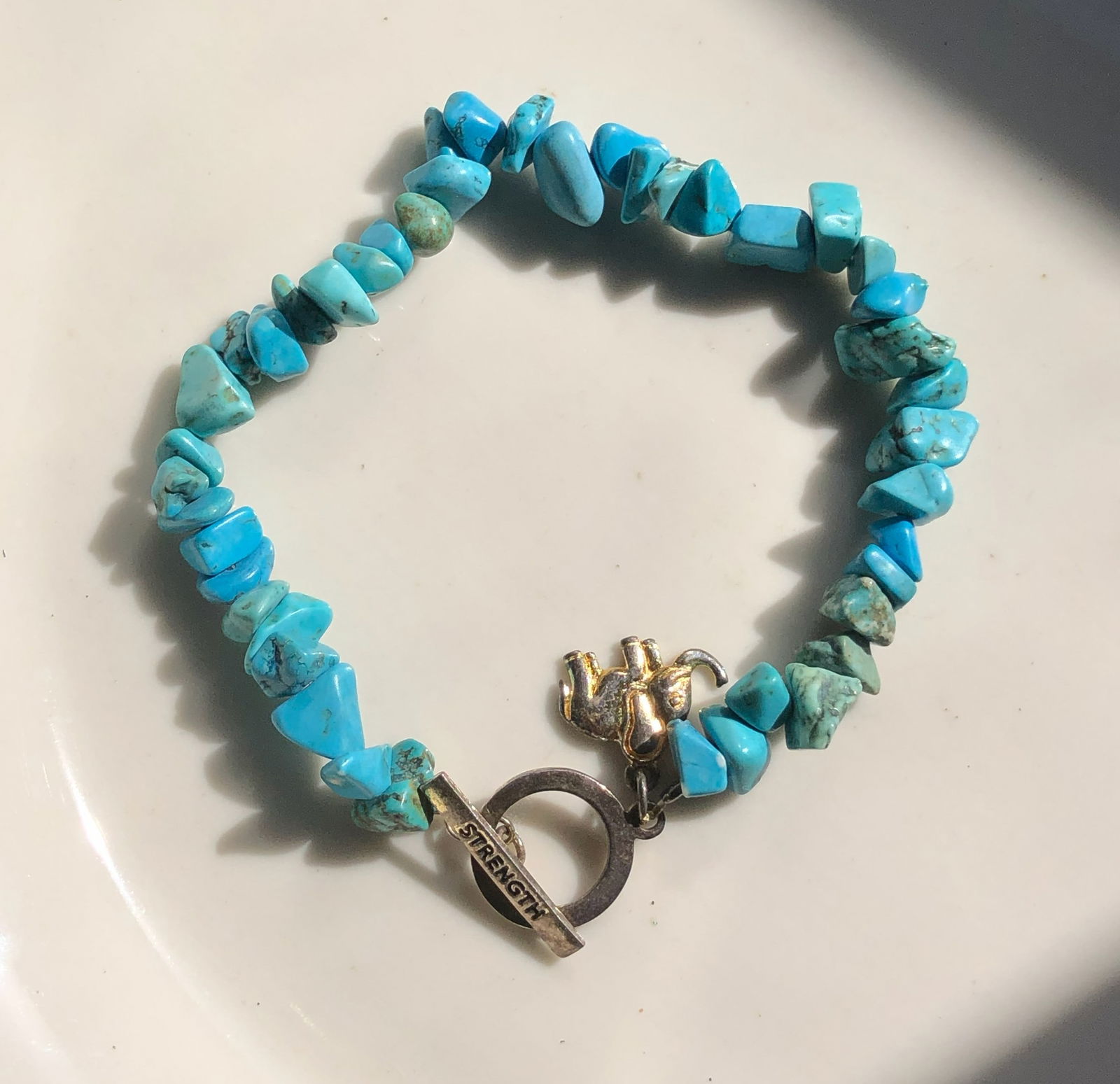 Turquoise Stone Bracelet: A beautiful turquoise stone bracelet with a Silver charm and 'Strength' inscribed clasp.