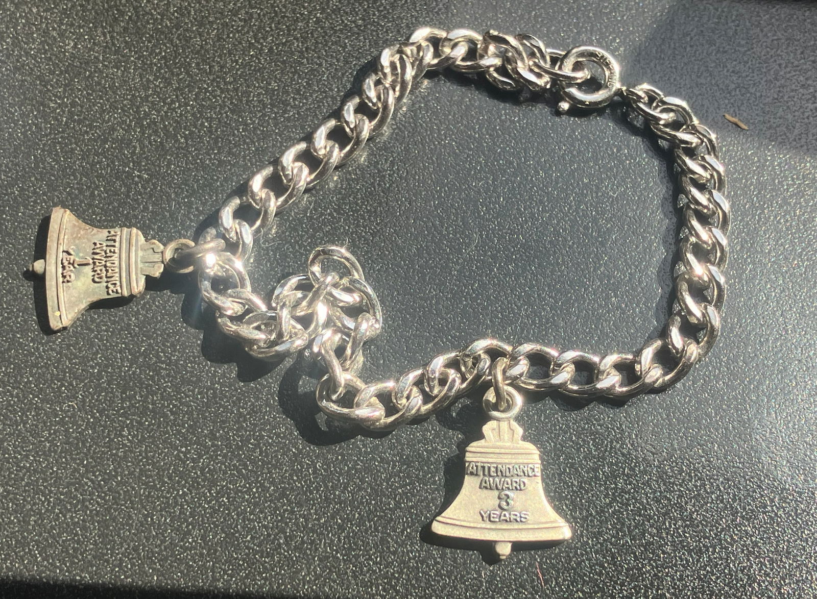 Attendance Award Silver Bracelet: A Silver bracelet with attendance award charms for 1 and 3 years.