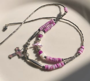 A beautiful pink beaded necklace featuring a cross pendant.