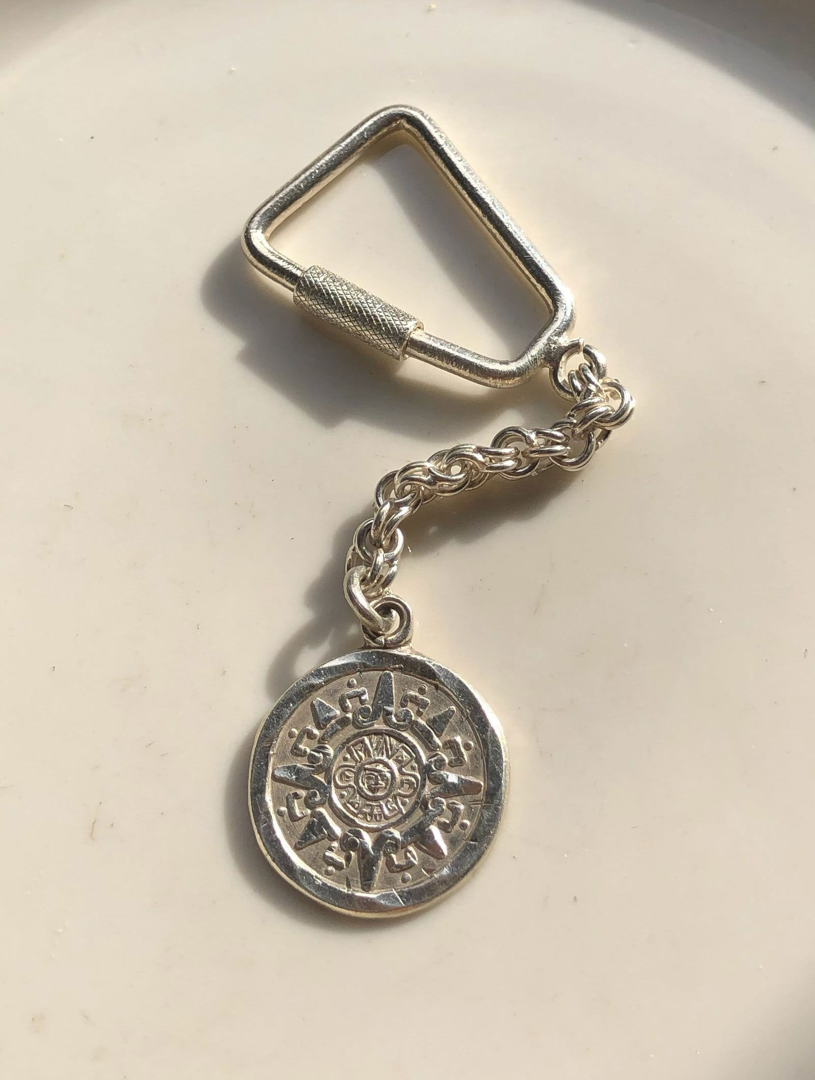 Silver Keychain with Sun Medallion: A stylish silver keychain featuring a sun medallion design.