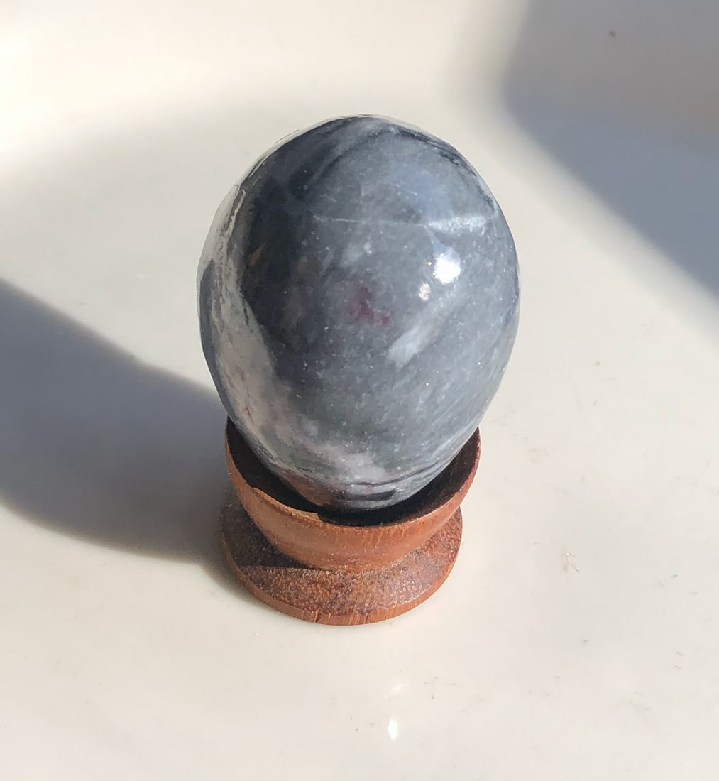 Polished Stone Egg: A beautifully polished stone egg with a wooden stand. Size: 1.5".