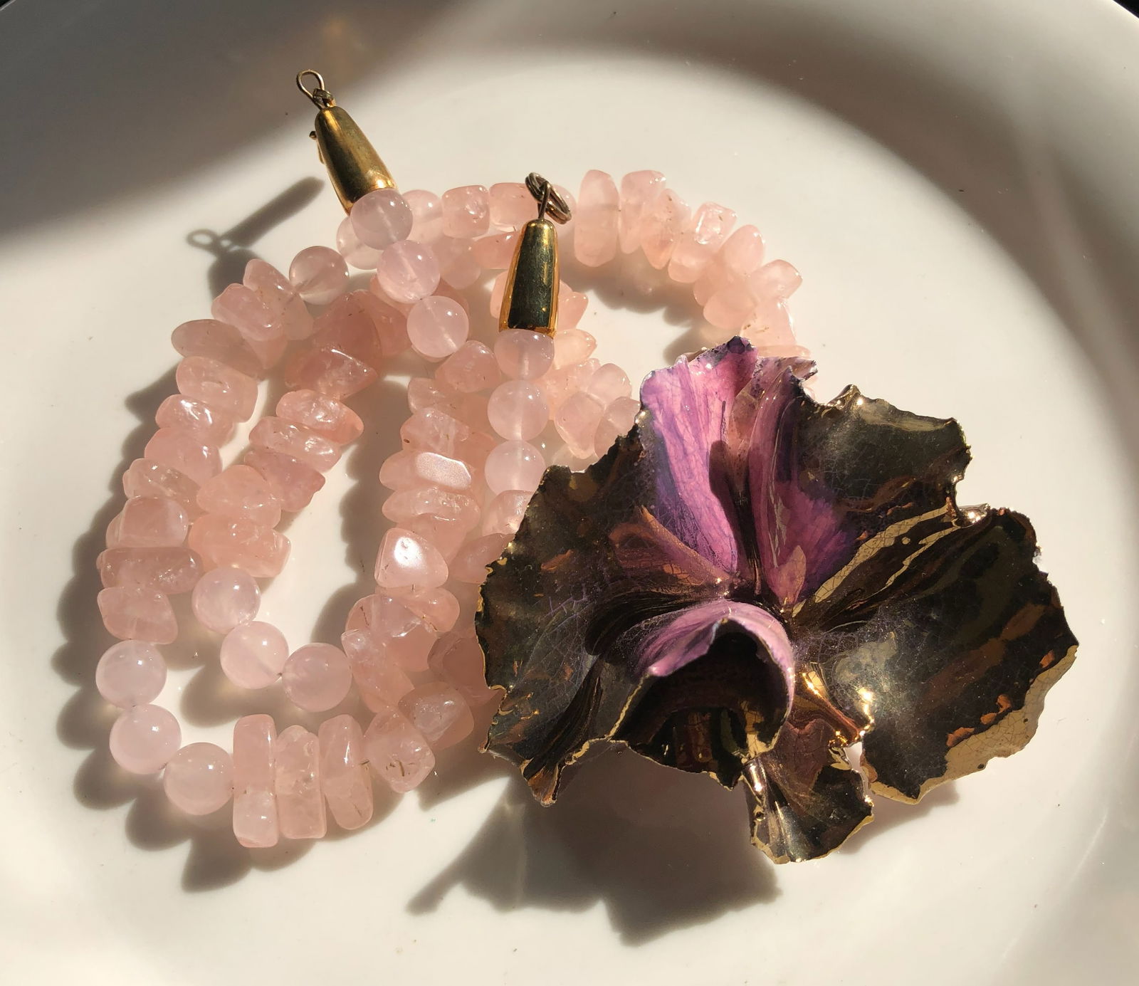 Rose Quartz Necklace with Floral Pendant: Elegant rose quartz necklace featuring a unique floral pendant with gold accents.