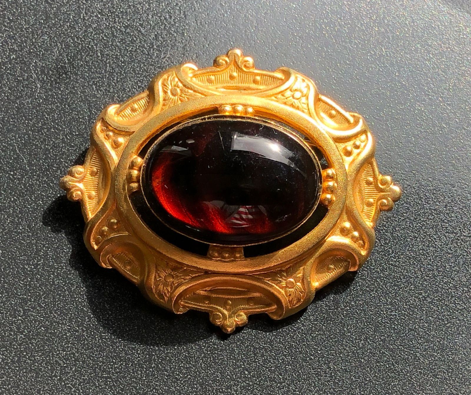 Vintage Brooch: A beautiful vintage brooch with intricate gold detailing and a deep red gemstone. Size 2".