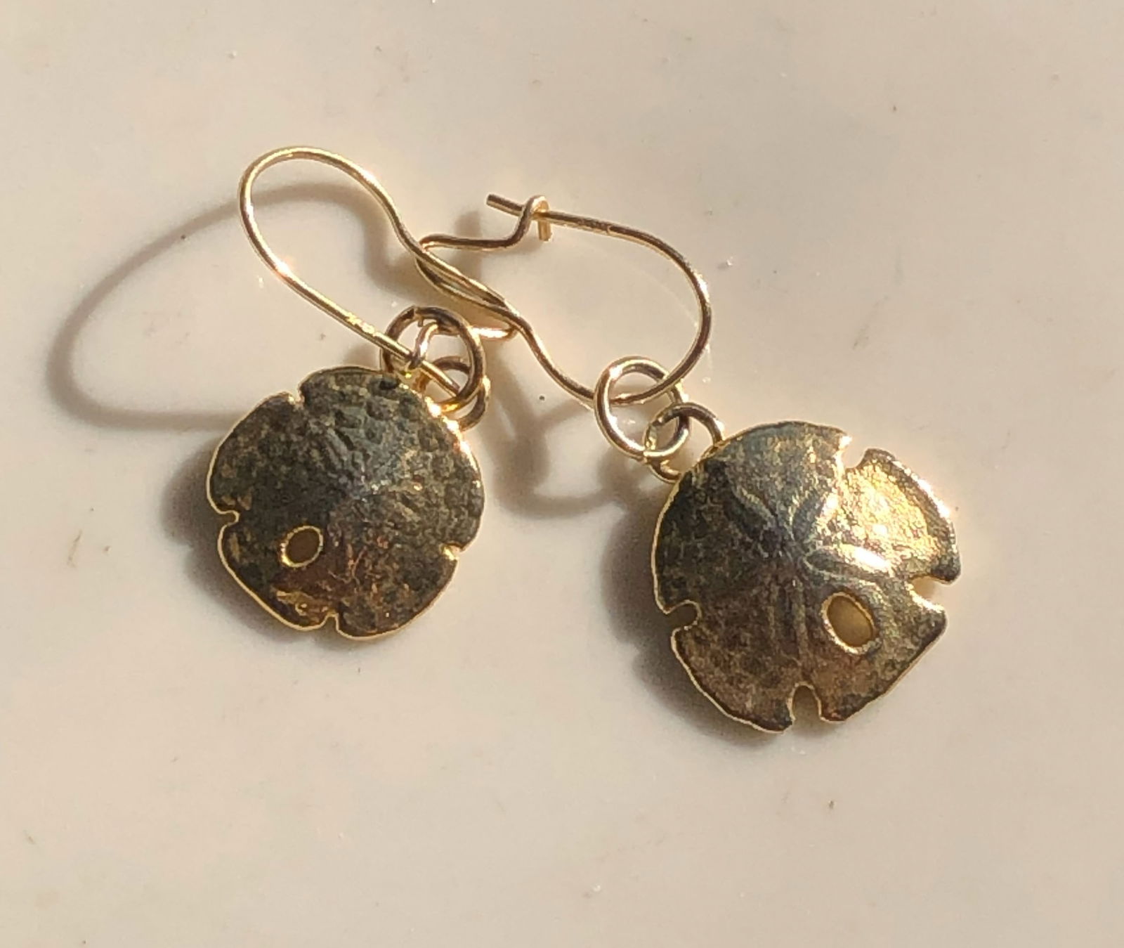 Gold Color Sand Dollar Earrings: Elegant gold color earrings shaped like sand dollars.