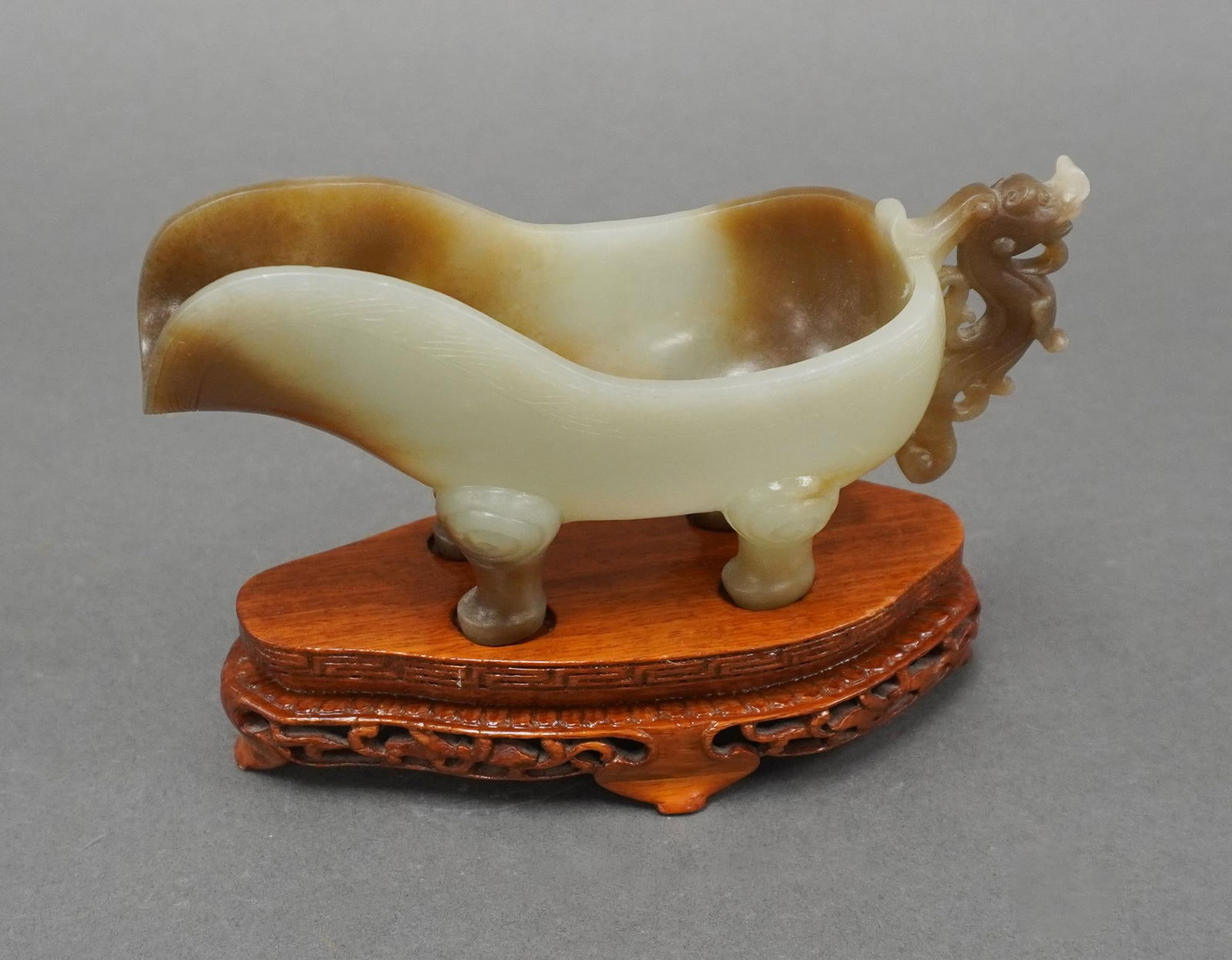 Chinese Archaic Style Carved Celadon-to-Russet Jade Zhou Ritual Water Pourer: Chinese Archaic Style Carved Celadon-to-Russet Jade Zhou Ritual Water Pourer, H on wood stand 4 3/8 in. (11.1 cm.)