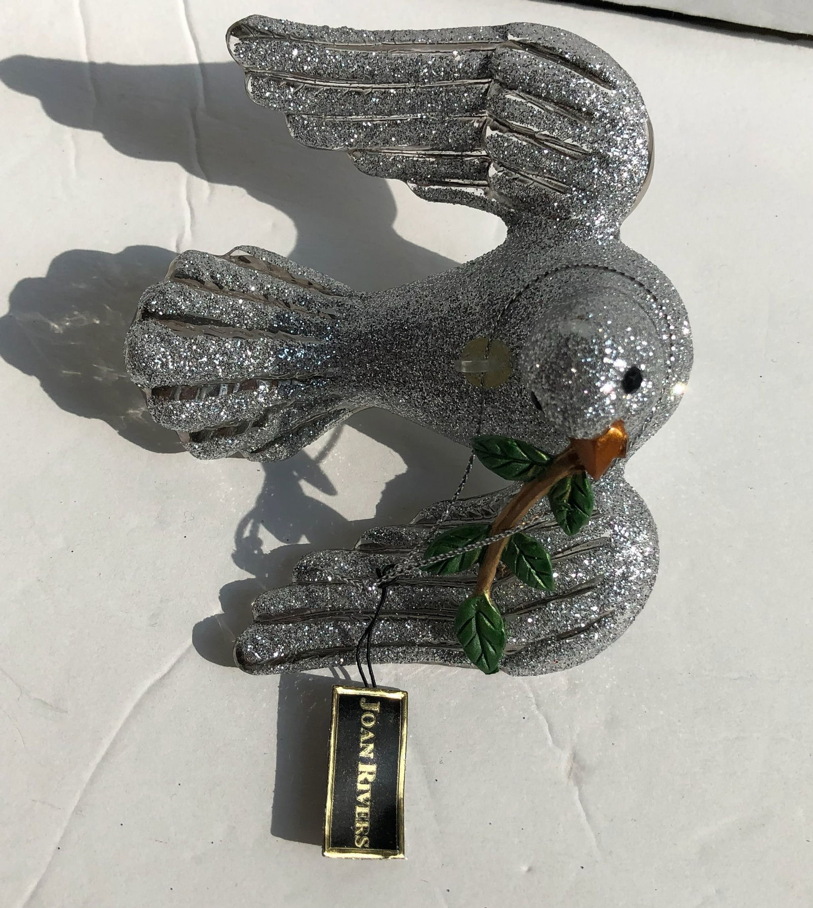 Joan Rivers Silver Glitter Dove Ornament: A Joan Rivers sparkling silver dove ornament with a branch, perfect for holiday decoration.