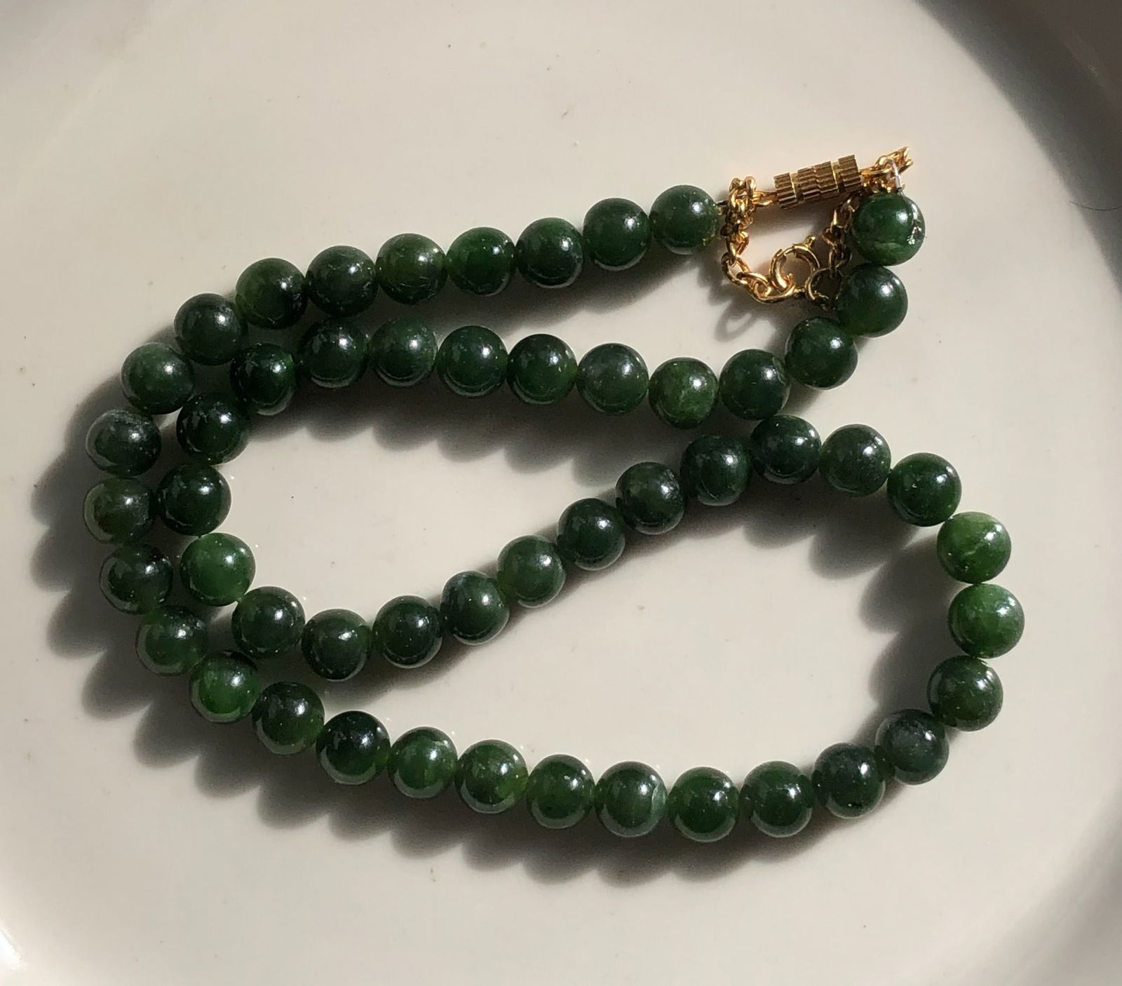 Green Jade Beaded Necklace: Elegant green jade beaded necklace with a gold color clasp. Length:16".