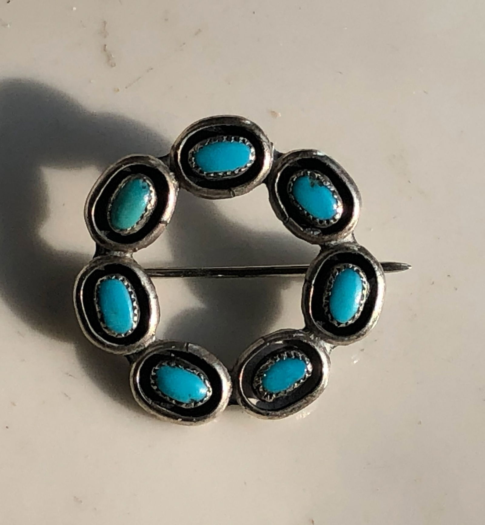 Turquoise Brooch: A beautiful brooch featuring turquoise stones set in a circular design.