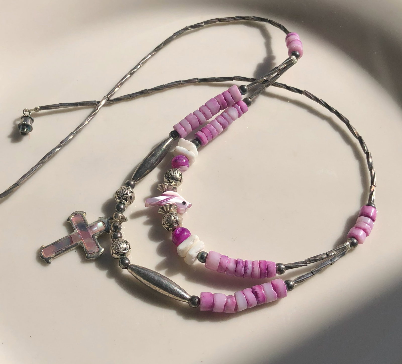 A beautiful pink beaded necklace featuring a cross pendant. (1 of 3)