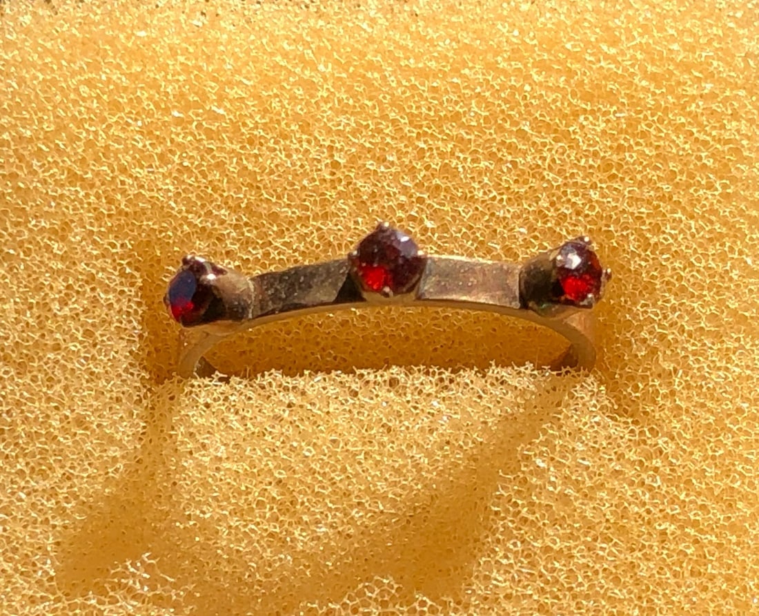 Triple Gemstone Ring: A beautiful ring featuring three red gemstones set in a gold color band, Size 7.