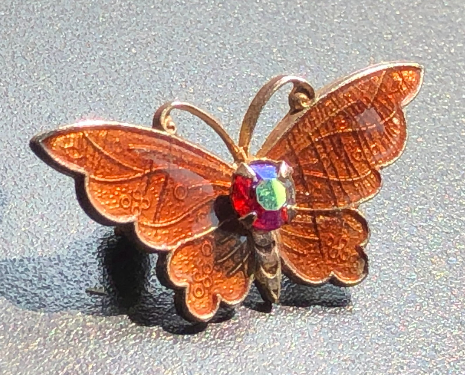 A beautifully crafted butterfly brooch with intricate details and a colorful gemstone (1 of 3)
