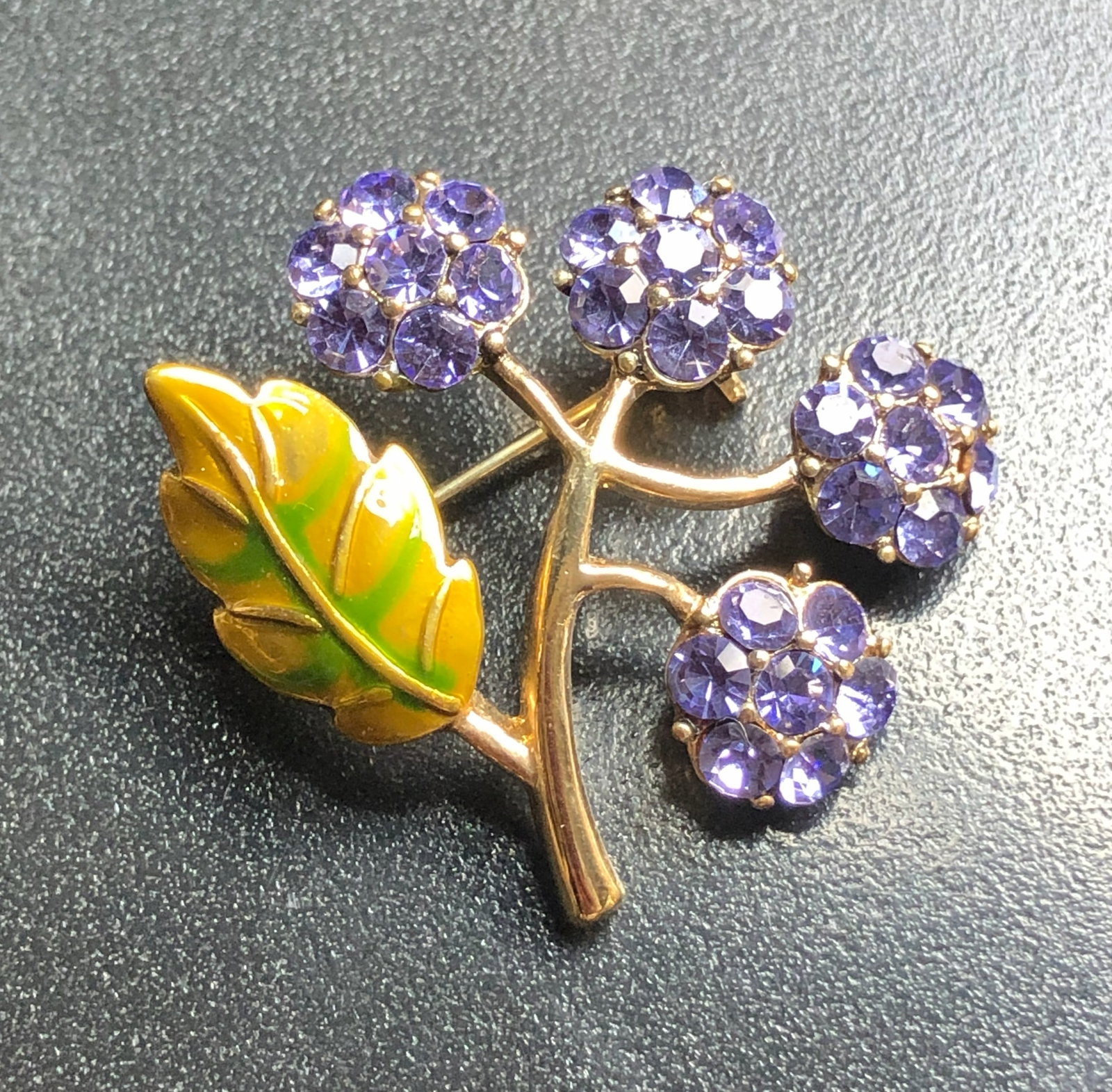 Floral Brooch: A beautiful floral brooch with purple gemstones and a green leaf design.