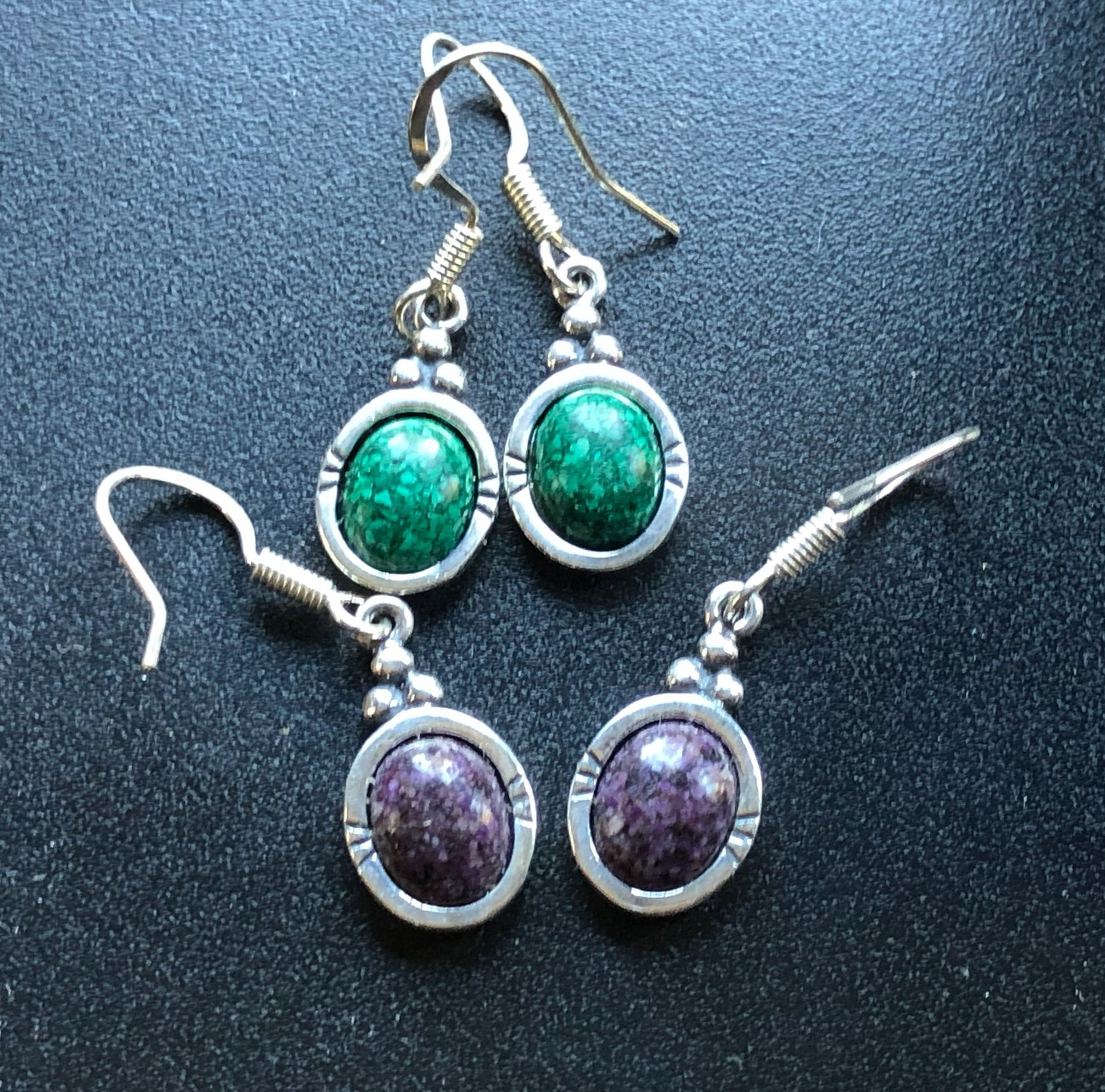 Two Pairs of Silver Earrings: Elegant gemstone earrings with a silver finish, featuring green and purple stones.