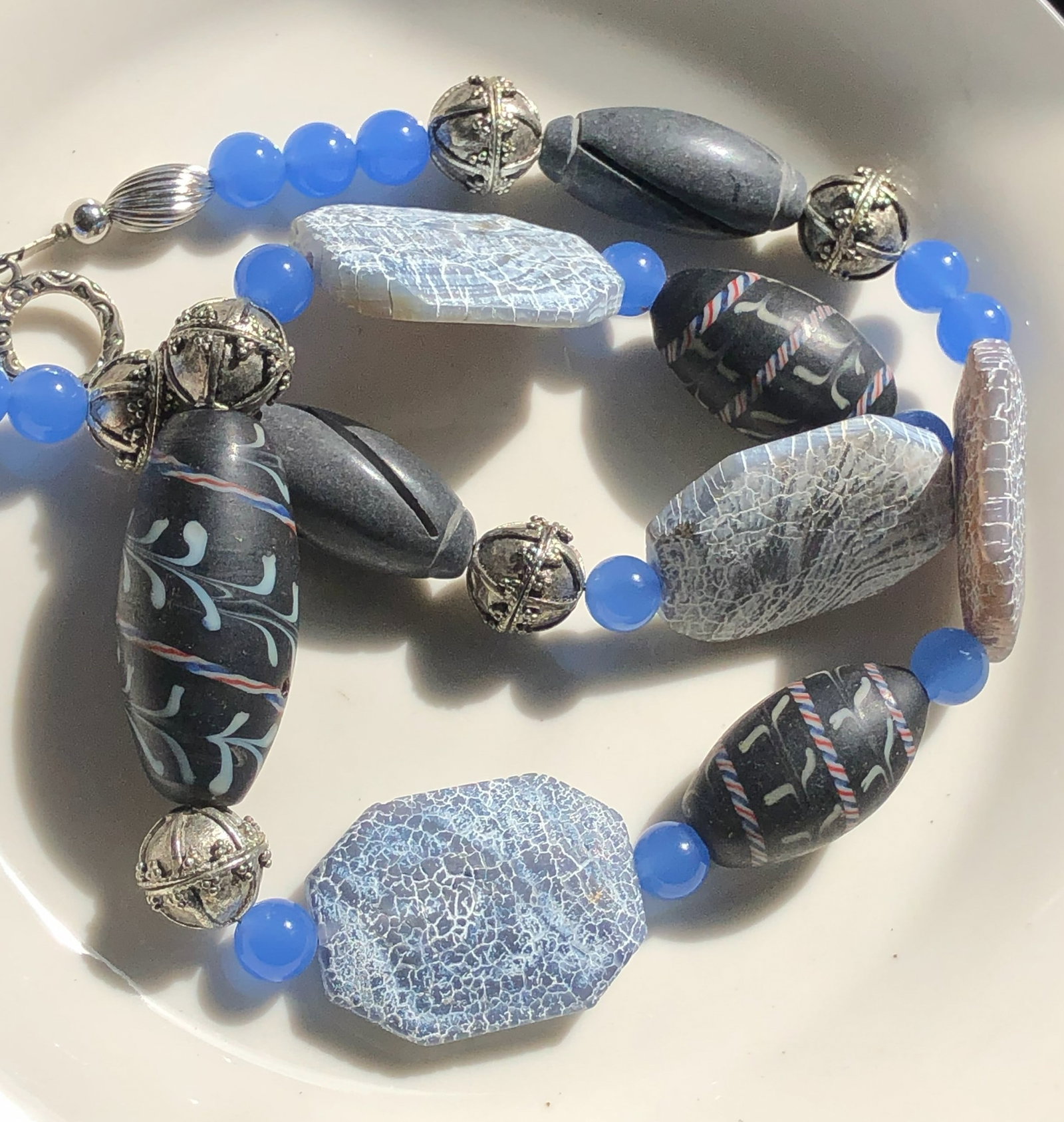 Blue Beaded Necklace: A stylish necklace featuring blue and silver color beads with intricate designs.